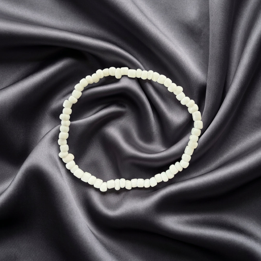 Full view of a handcrafted bracelet made with small white beads on elastic cord.