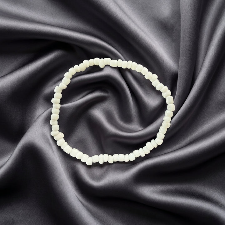 Full view of a handcrafted bracelet made with small white beads on elastic cord.