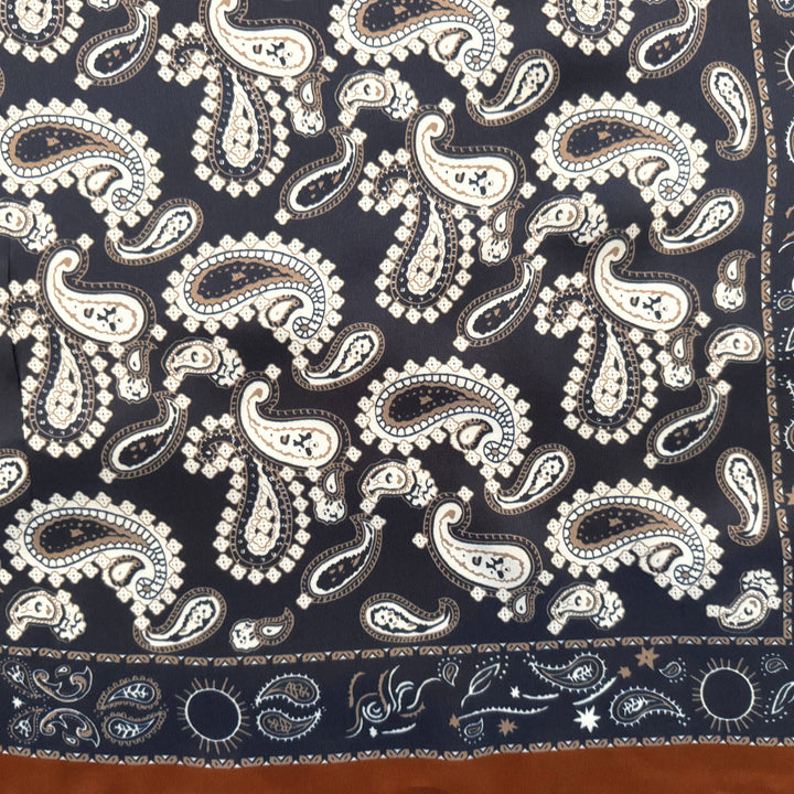 Close-up of white and beige paisley pattern on navy silk fabric.