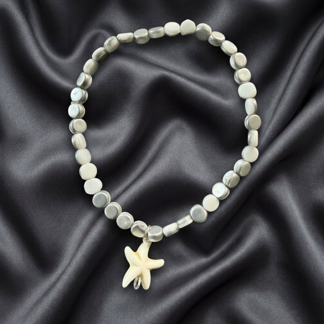 Full view of a white and silver beaded bracelet featuring a white seastar charm in a minimalist stackable design.