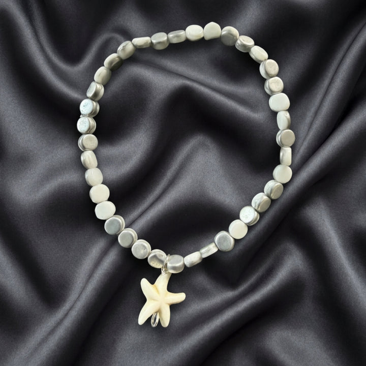 Full view of a white and silver beaded bracelet featuring a white seastar charm in a minimalist stackable design.