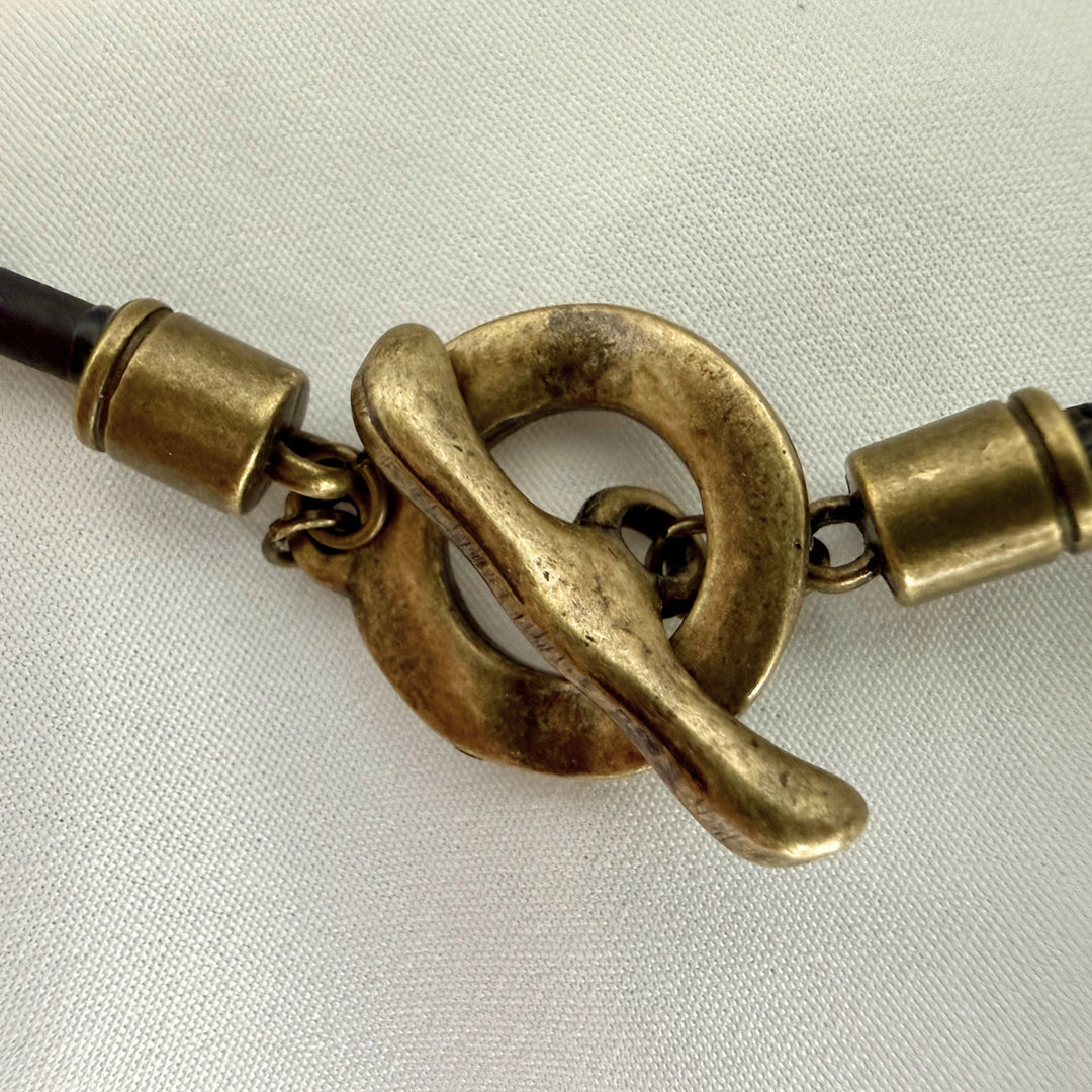 Close-up of necklace closure showing hook fastening system and black cork cord on a handcrafted pendant necklace.