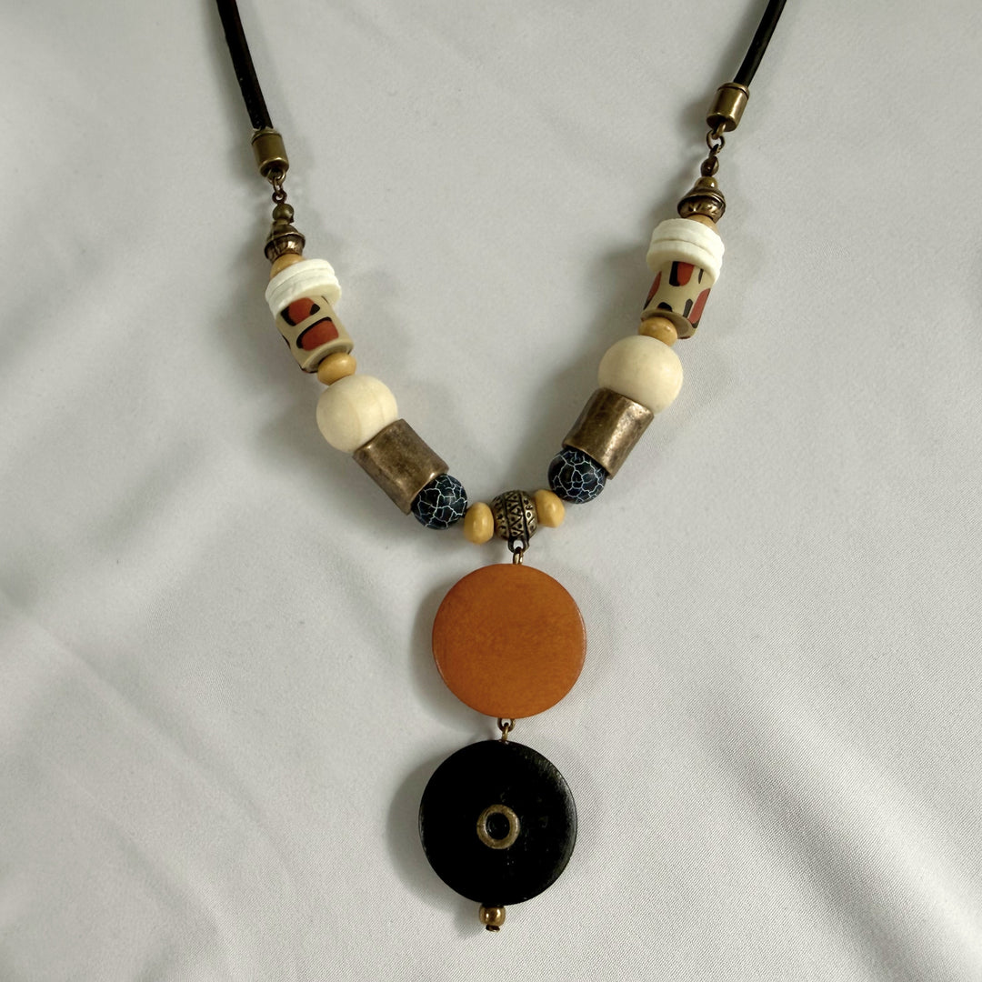 Top angled view of a handcrafted wood and agate pendant necklace showing layered natural materials on black cord.