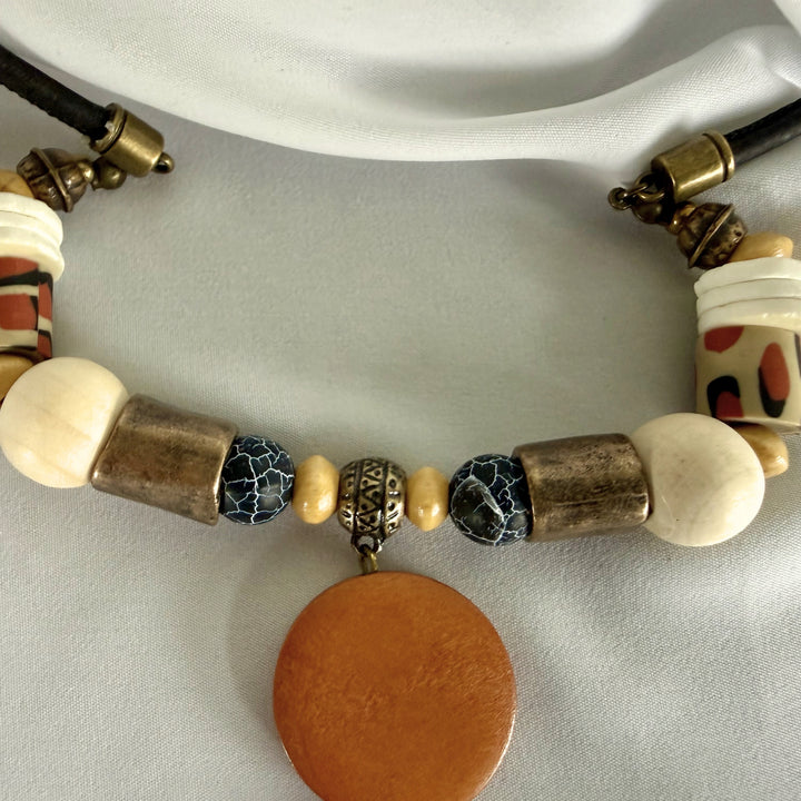 Extreme close-up of handcrafted necklace pendant showing crackle agate, wood, and polymer clay texture details.