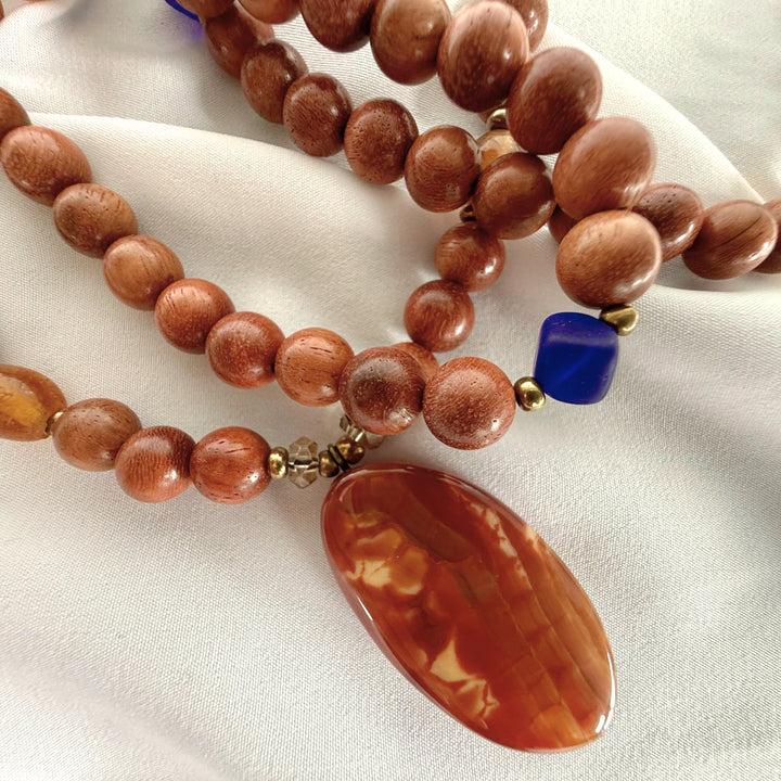 Side close-up of a handcrafted necklace showing wooden beads and amber beads with mixed textures and colour contrast.