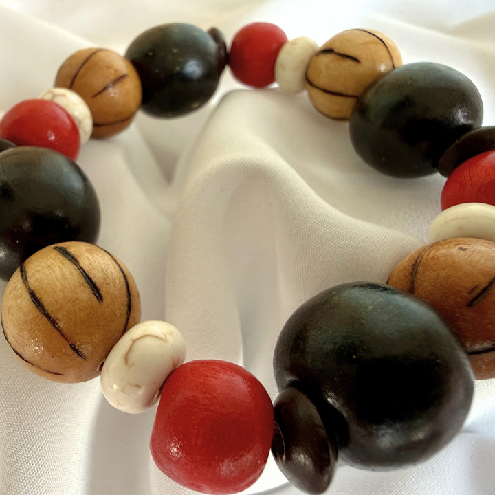 Close-up of maroon, black, and brown beads combining wood and howlite in a handcrafted bracelet.