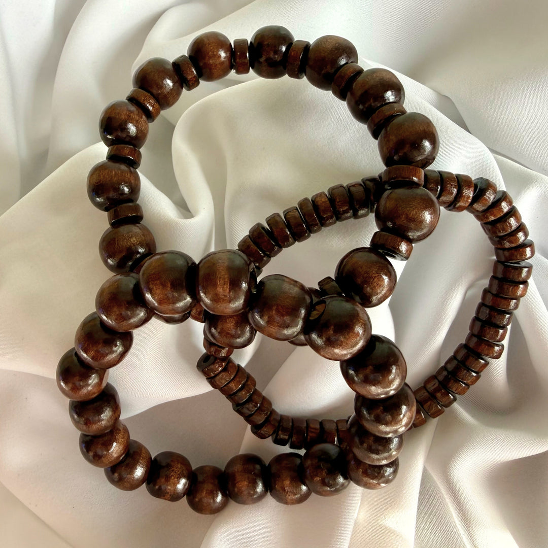 Three brown wooden beaded bracelets spread out together, showing each design variation side by side.