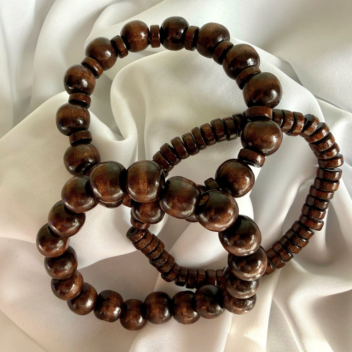 Three brown wooden beaded bracelets spread out together, showing each design variation side by side.
